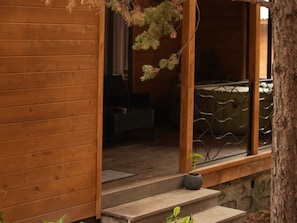 Fachada de madera con una escalera de piedra que conduce a un porche cubierto.