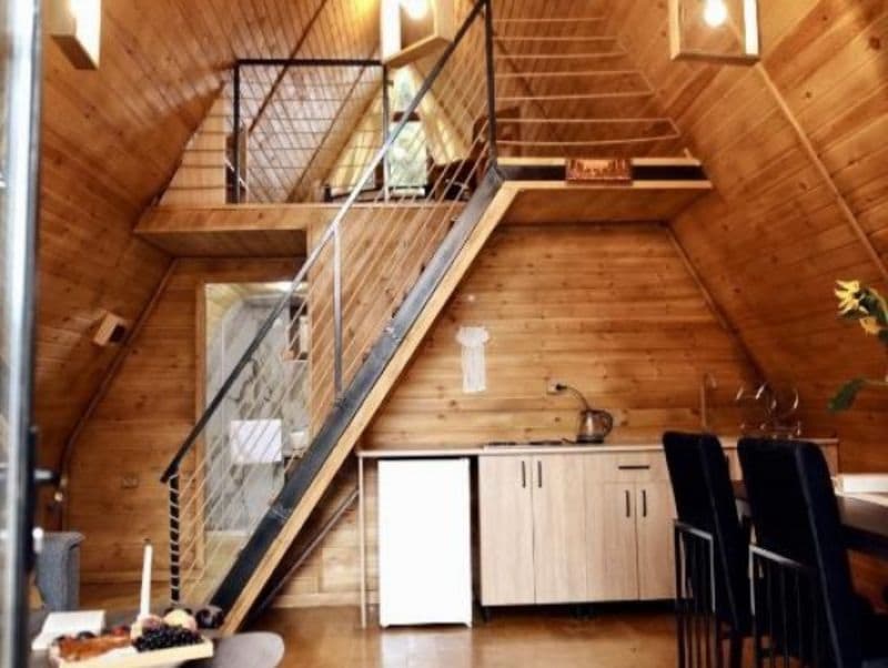 A wooden interior with a kitchen area, a staircase, and a dining table.