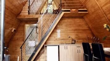 A wooden interior with a kitchen area, a staircase, and a dining table.
