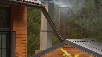 Una cabaña de madera con techo de metal, una chimenea y una ventana.