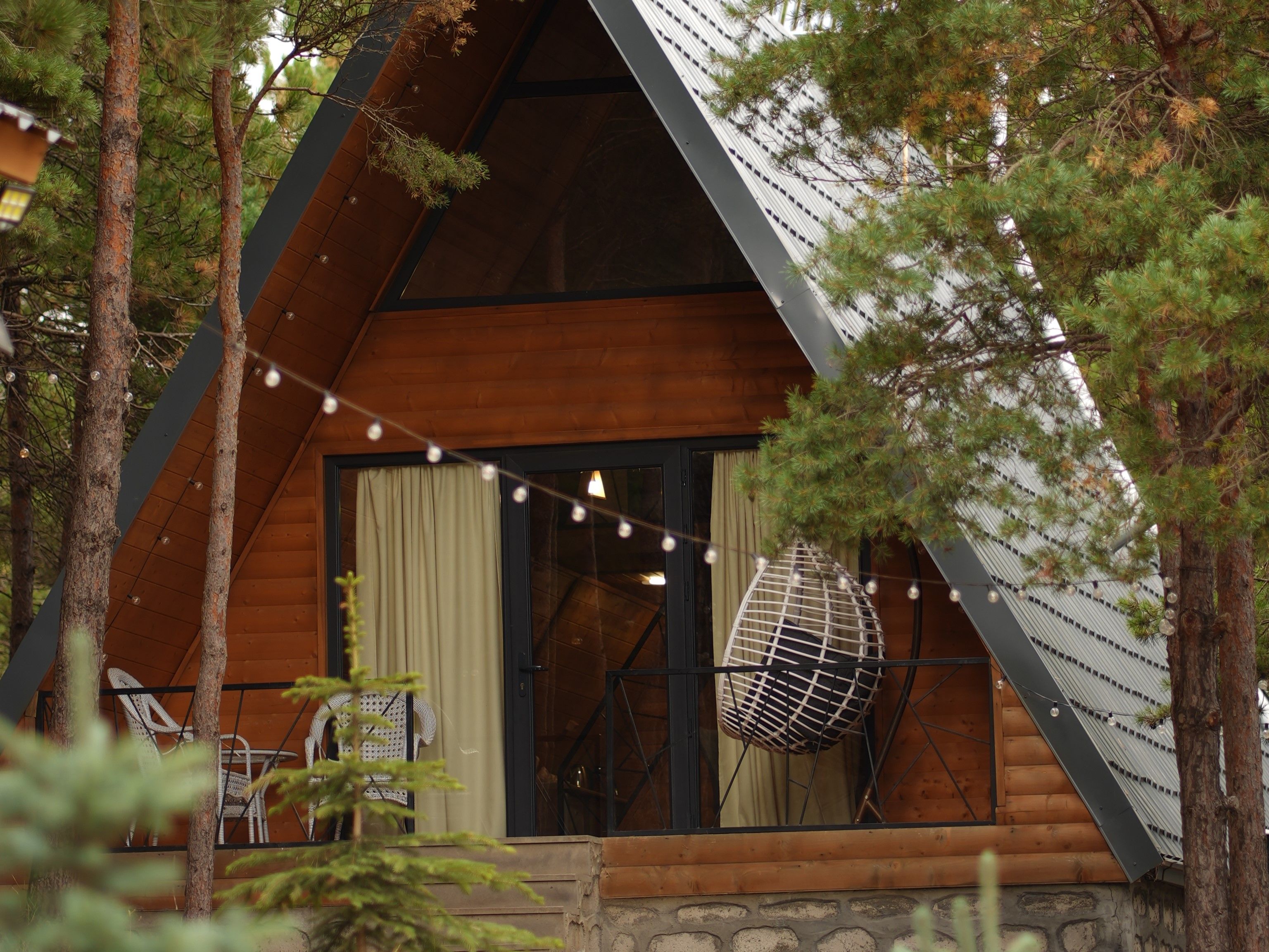 A cabin with a sloped roof, large windows, and a balcony with outdoor seating.