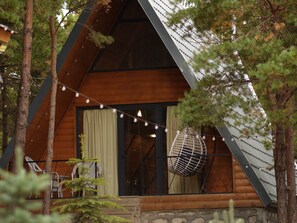 A cabin with a sloped roof, large windows, and a balcony with outdoor seating.