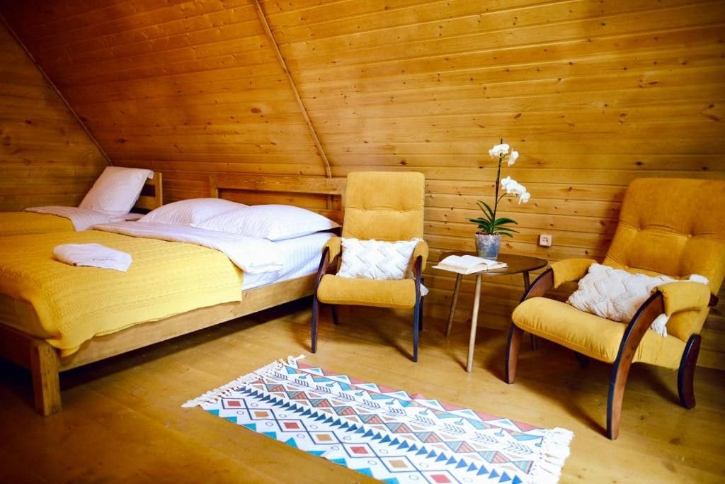 Una habitación acogedora con una cama, dos sillones, una mesita y una planta en maceta.