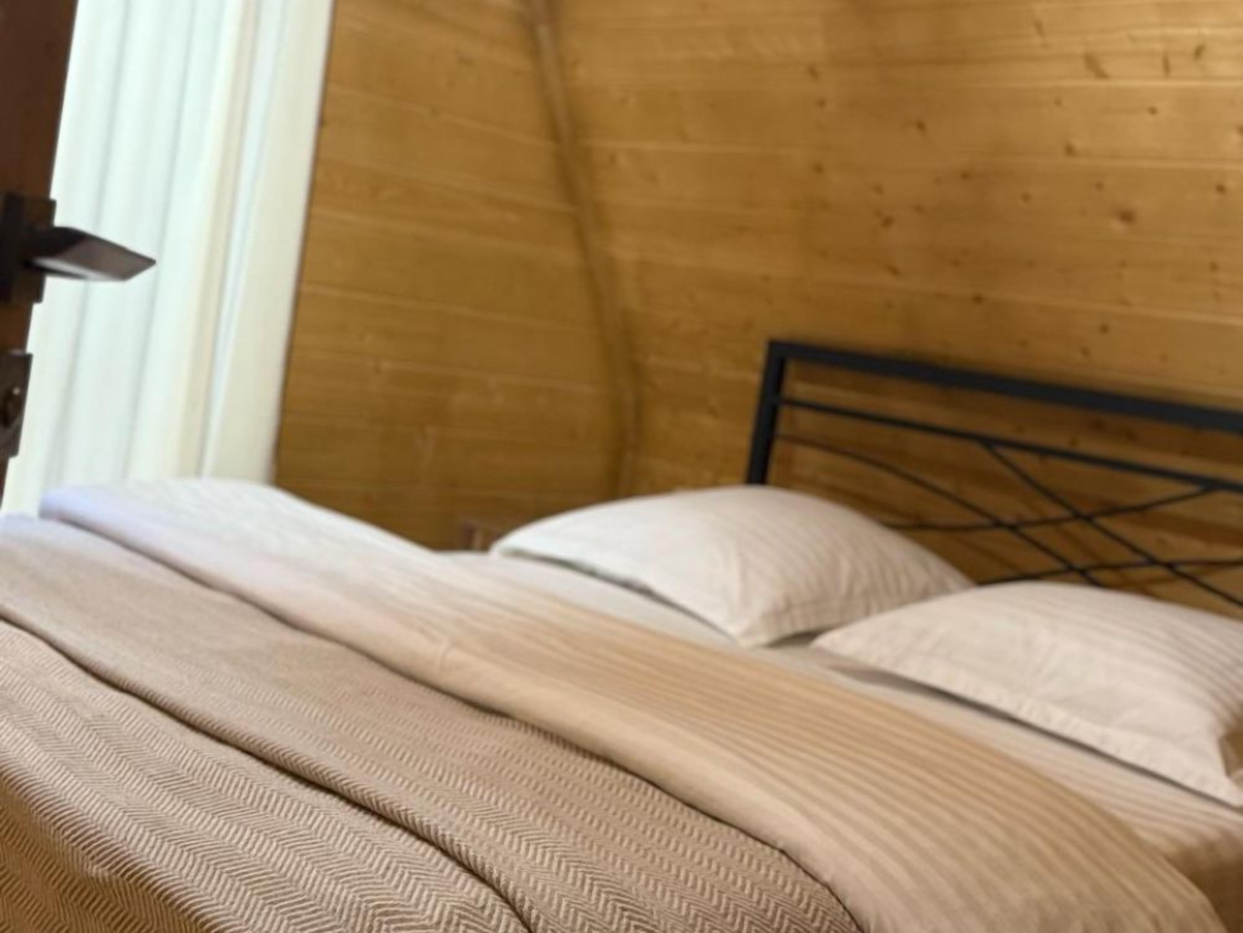 A bed with a wooden headboard and a herringbone-patterned bedspread.