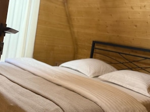 Una cama con cabecera de madera y colcha estampada en patrón de espiga.