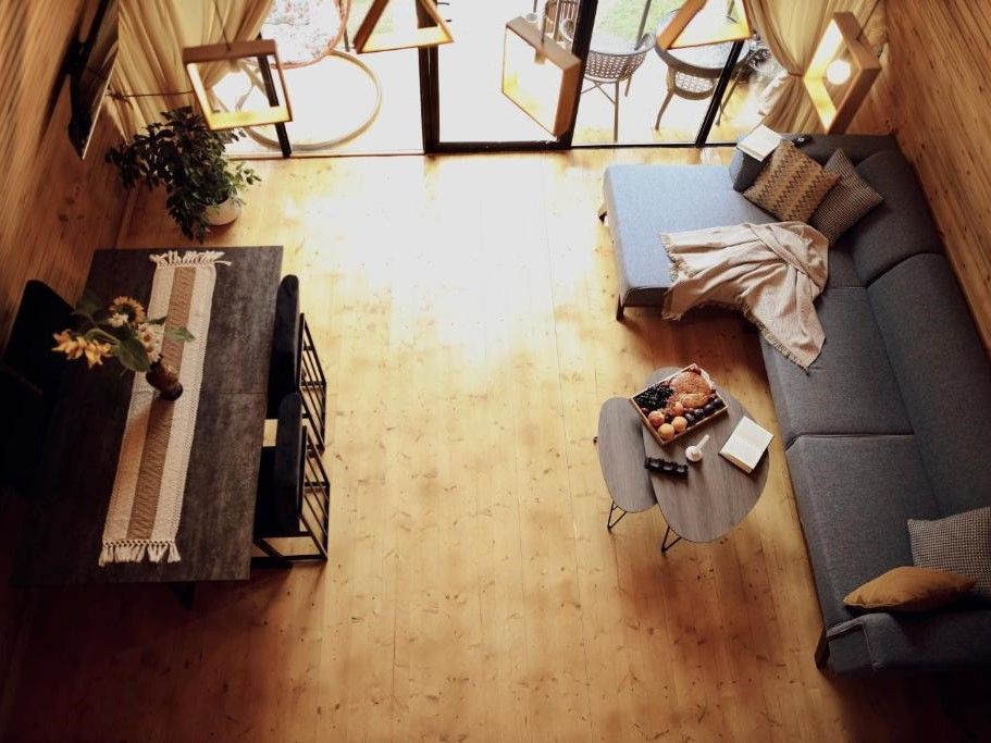 Ein gemütliches Wohnzimmer mit einer Couch, einem Couchtisch und einem Esstisch, dekoriert mit einer Pflanze und Blumen.
