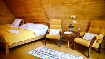 A cozy room with a bed, two armchairs, a small table, and a potted plant.