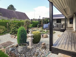 A covered outdoor area with a wooden deck, a stone lantern, and a garden with various plants and rocks.