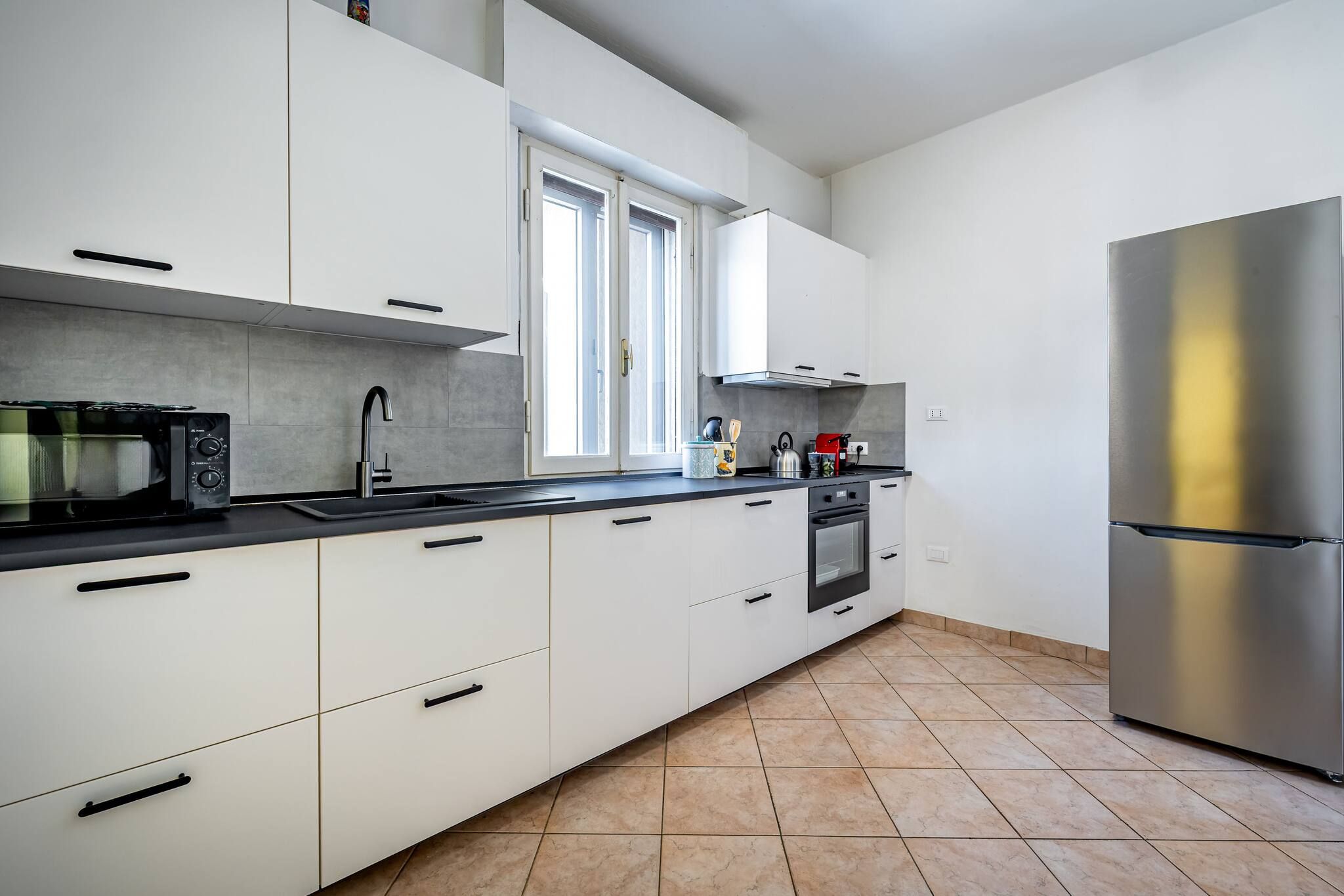 Une cuisine moderne avec des armoires blanches, un réfrigérateur en acier inoxydable, un four à micro-ondes et une cuisinière.