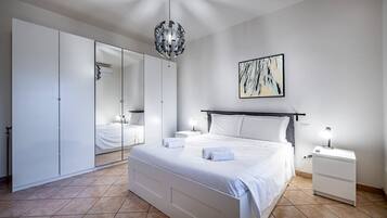 Un dormitorio moderno con una cama grande, una mesita de noche con lámpara, un armario y una lámpara en el techo.