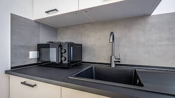 A modern kitchen with a black countertop, a built-in sink, and a toaster.