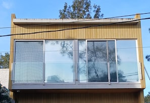 Edifício com telhado plano e janelas amplas refletindo árvores.