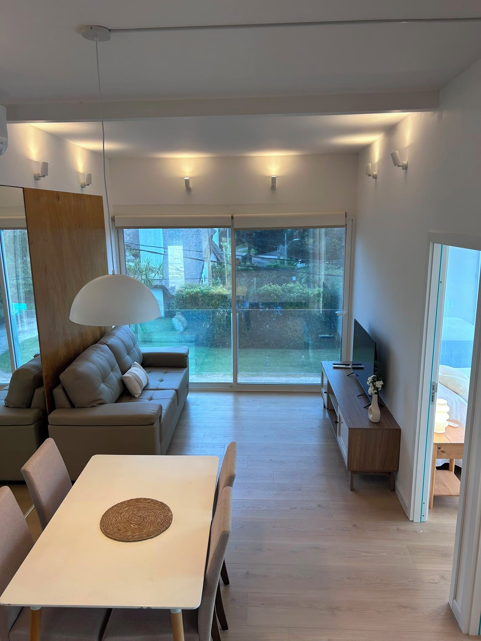 Uma sala de estar moderna com um sofá, uma mesa de jantar e uma TV.