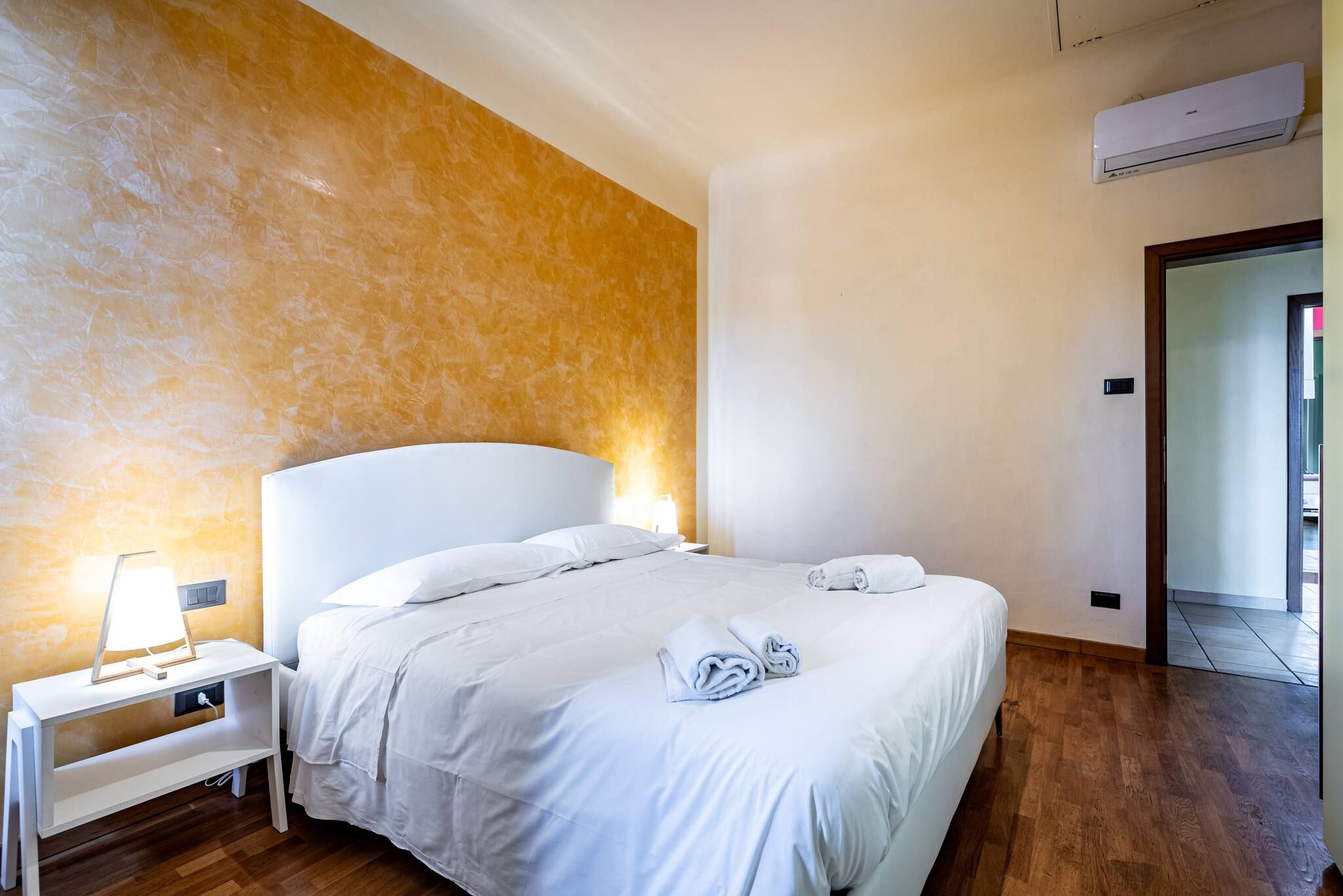 A hotel room with a bed, bedside table, lamp, and towels.
