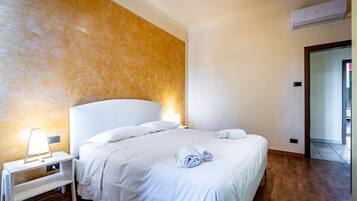 A hotel room with a bed, bedside table, lamp, and towels.
