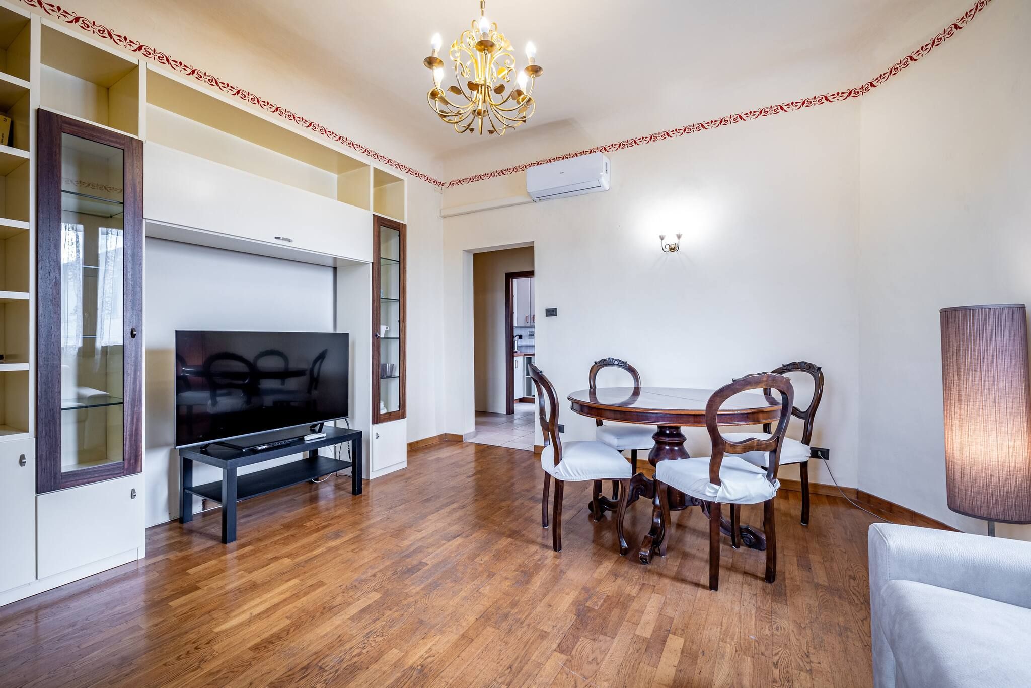 A living room with a flat-screen TV, wooden dining table, and chairs.