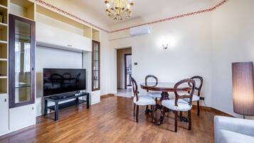 A living room with a flat-screen TV, wooden dining table, and chairs.