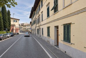 Une rue bordée de voitures garées et un immeuble doté de nombreuses fenêtres et portes.