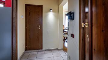 Un pasillo con una puerta de madera, una lámpara en la pared y un timbre.