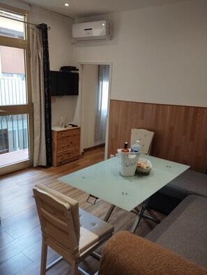 Ein modernes Zimmer mit Glastisch, einer Couch, einem Holzschrank und einem Fernseher.