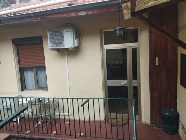 Ein Gebäudefassade mit Metallgeländer, einer Tür, einem Fenster mit Rollo und einer an der Wand montierten Klimaanlage.