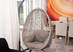A room with a hanging chair, a table with chairs, and a colorful tapestry. - The Willow House | 4BR • Garden • Parking for 2 - Pass the Keys (Sidcup)