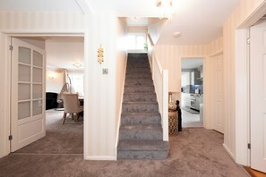 Un escalier menant à un deuxième étage, avec une petite plateforme recouverte de moquette.