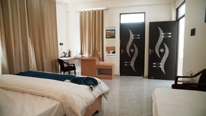 Ein Hotelzimmer mit Bett, Schreibtisch, Stuhl und zwei Türen mit dekorativen Verzierungen.