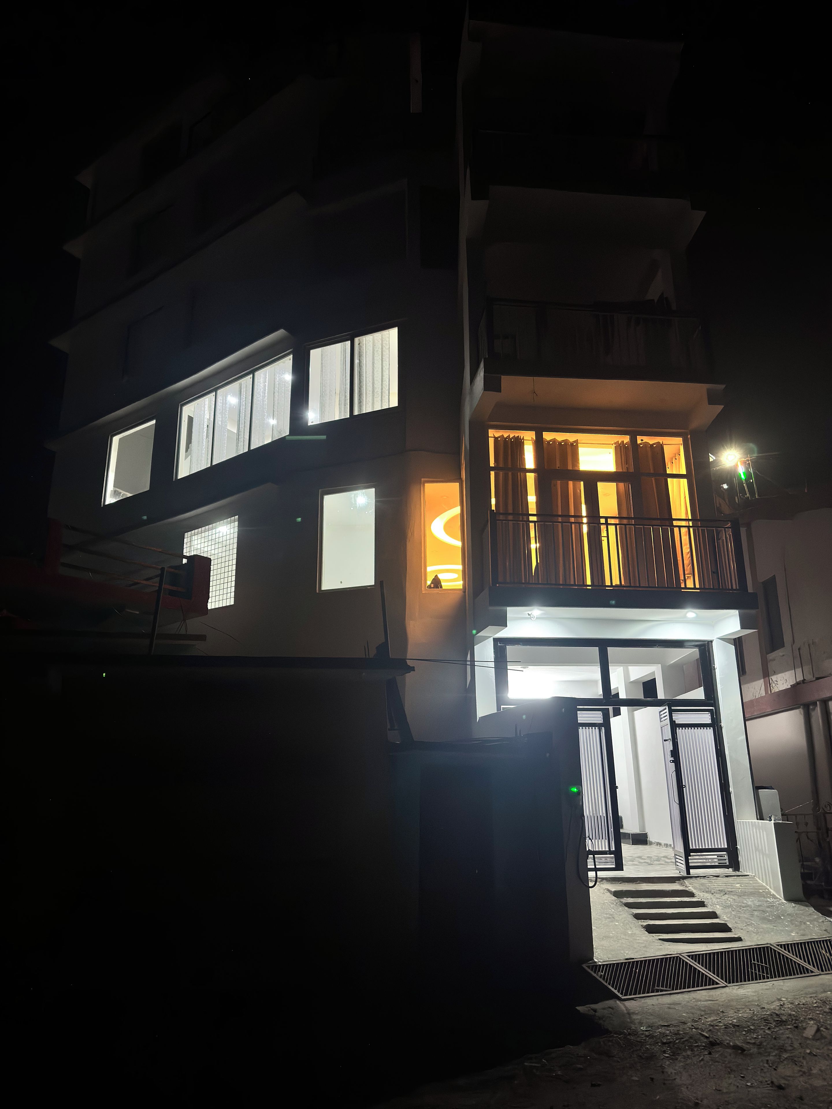 Un immeuble à plusieurs étages, doté de fenêtres illuminées et d’un balcon.