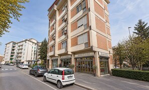 Un edificio de varios pisos con locales comerciales en la planta baja, incluyendo una panadería y un café.