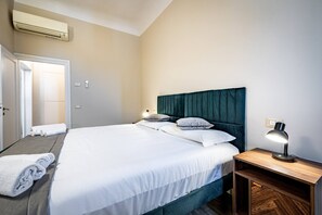 A neatly made bed with white linens, a teal headboard, and a bedside table with a lamp. - Scala 111 3P (Florence)