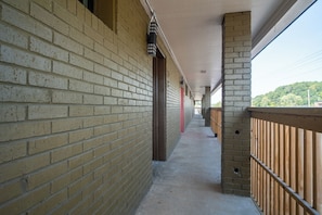 Un pasillo con paredes de ladrillo, barandas de madera y piso de concreto.