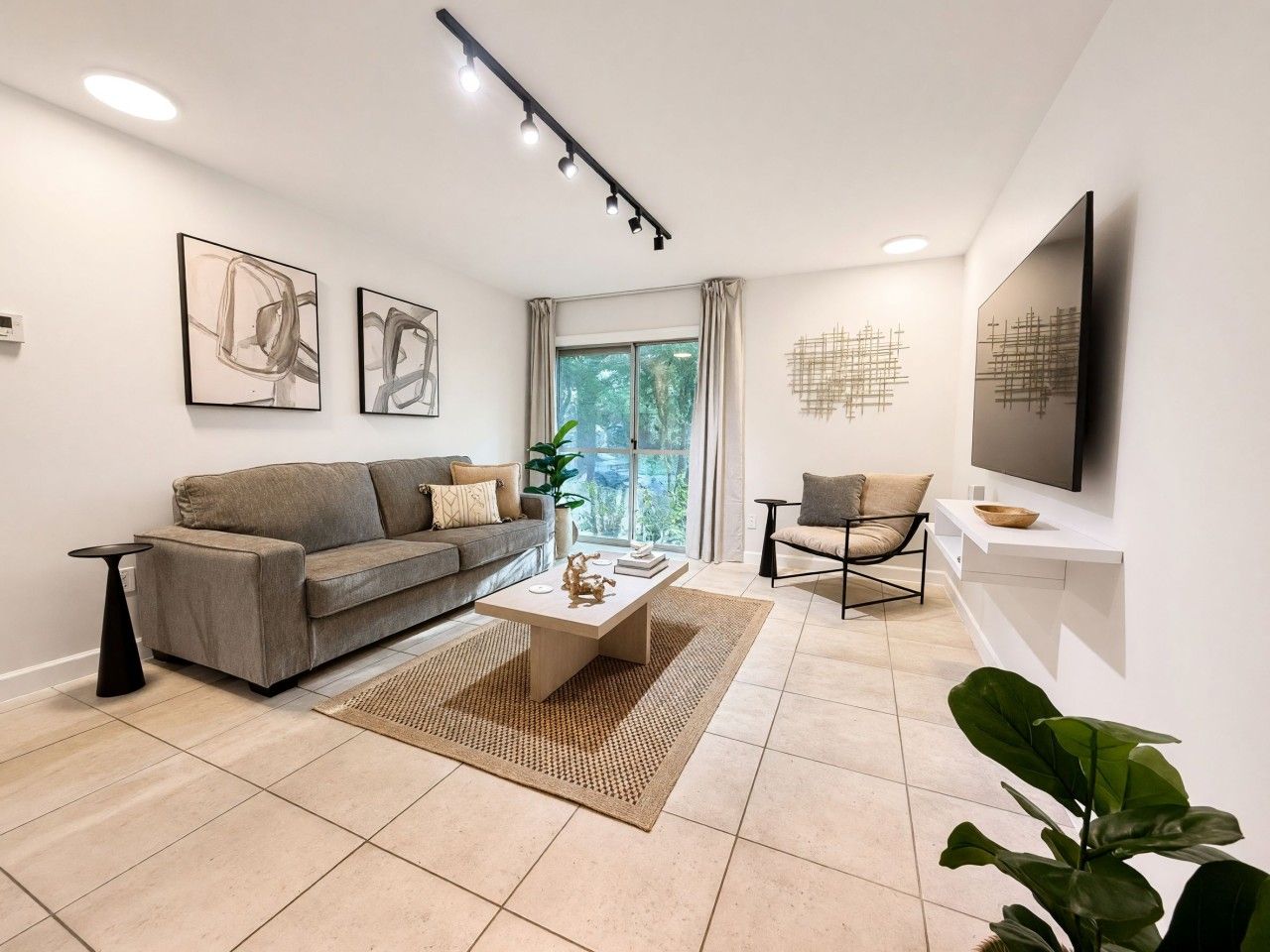 A modern living room with a sofa, coffee table, and a TV mounted on the wall.