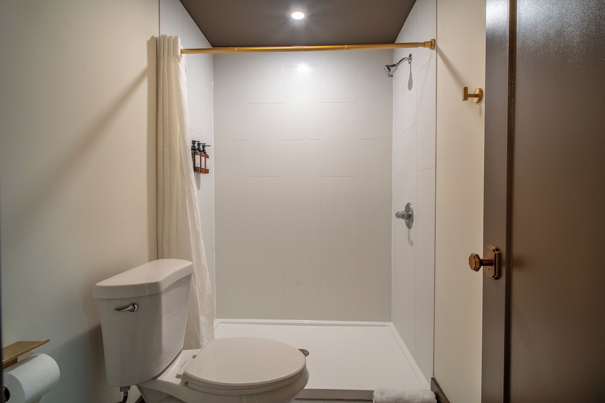 A bathroom with a toilet, shower, and a towel rack.
