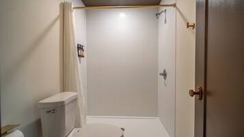 A bathroom with a toilet, shower, and a towel rack.