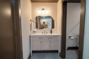 A bathroom with a vanity, a mirror, a light fixture, and a toilet.