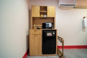A compact kitchenette with a microwave, refrigerator, and wooden cabinetry.
