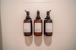 Três frascos de produtos para cabelo apoiados em uma parede.
