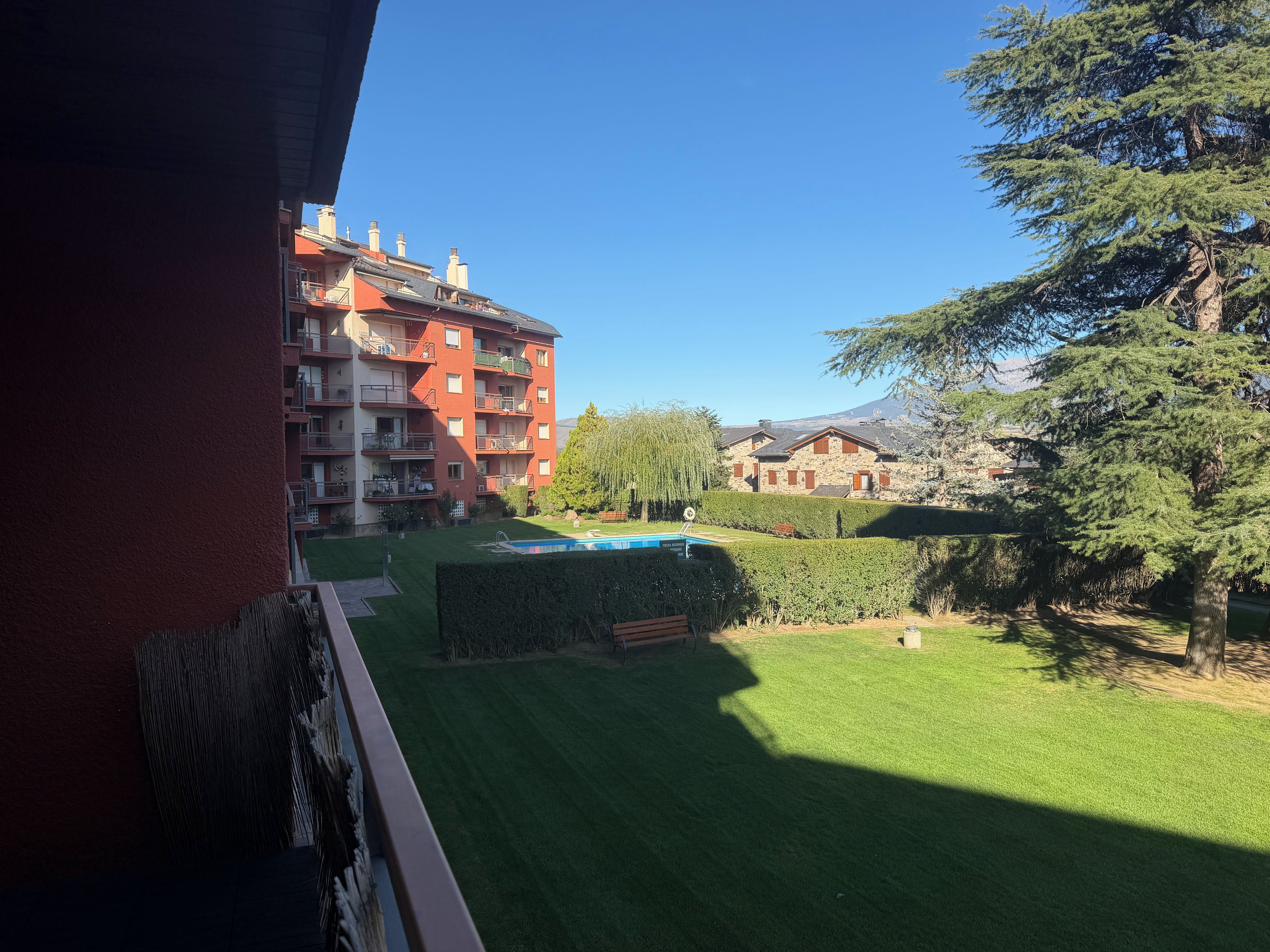 Zona residencial con piscina, césped cuidado y vistas a la montaña.