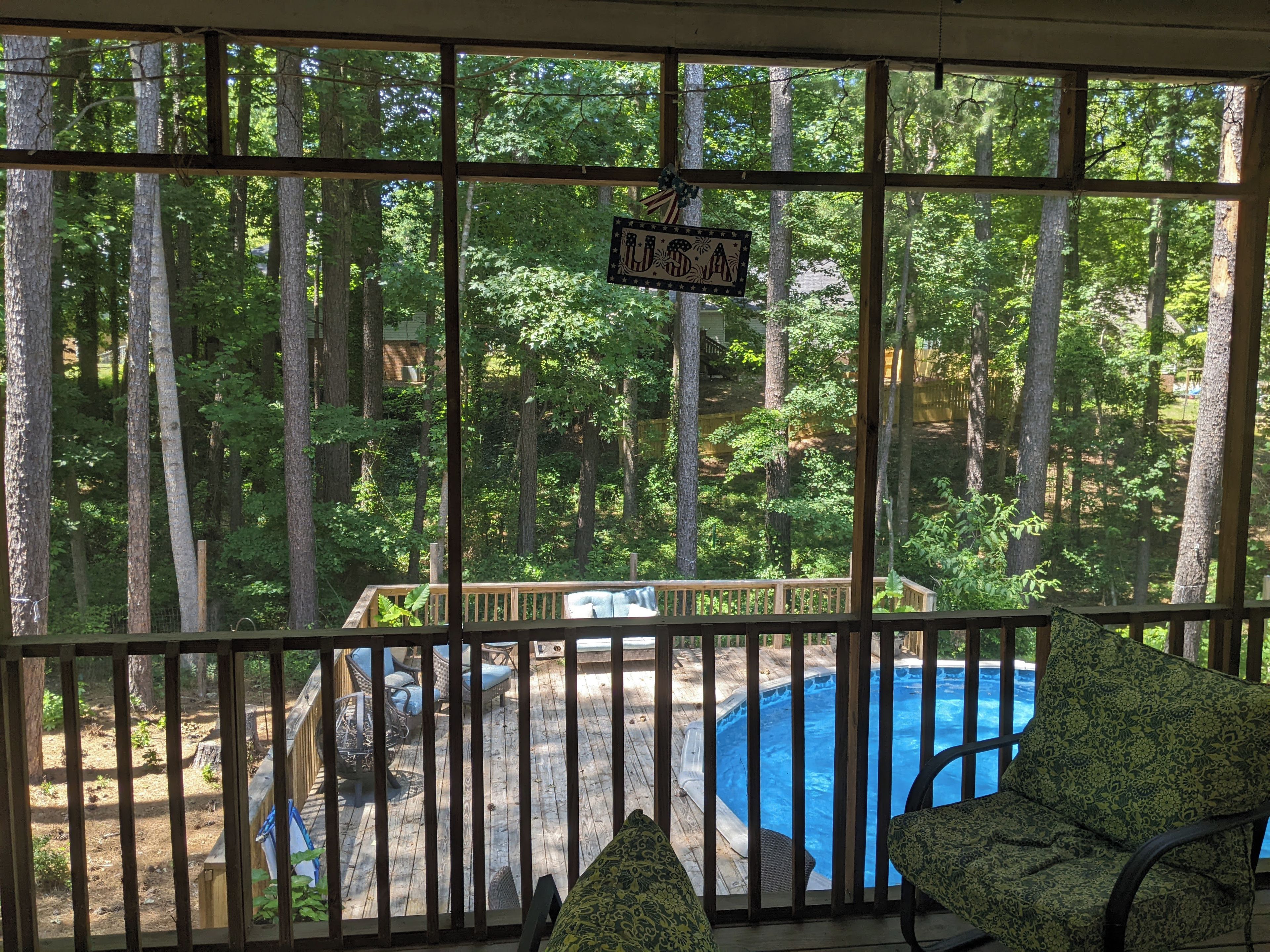 Une terrasse en bois avec un jacuzzi, entourée de grands arbres, et une pancarte sur laquelle on peut lire « États-Unis ».