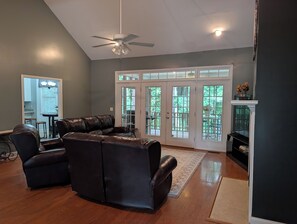 A living room with a sectional sofa, a ceiling fan, and a view through French doors to an outdoor deck. - Gorgeous 4-bedroom home with pool. 5 min from Lake Murray (Lexington)