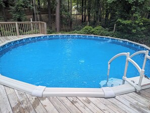 An above-ground swimming pool with a wooden deck and a metal ladder. - Gorgeous 4-bedroom home with pool. 5 min from Lake Murray (Lexington)