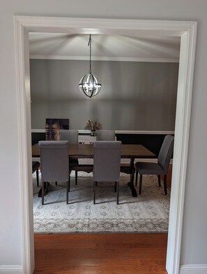 A dining room with a wooden table, four chairs, a chandelier, and a patterned rug. - Gorgeous 4-bedroom home with pool. 5 min from Lake Murray (Lexington)