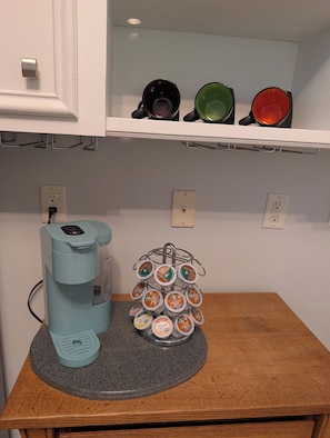 A kitchenette with a Keurig coffee maker, a mug rack with various coffee pods, and a countertop. - Gorgeous 4-bedroom home with pool. 5 min from Lake Murray (Lexington)