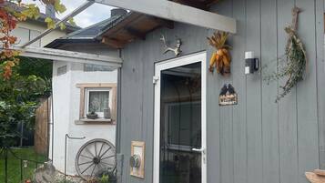 Une cabane rustique, ornée d’une girouette, d’une pancarte de bienvenue et d’une brouette devant l’entrée.