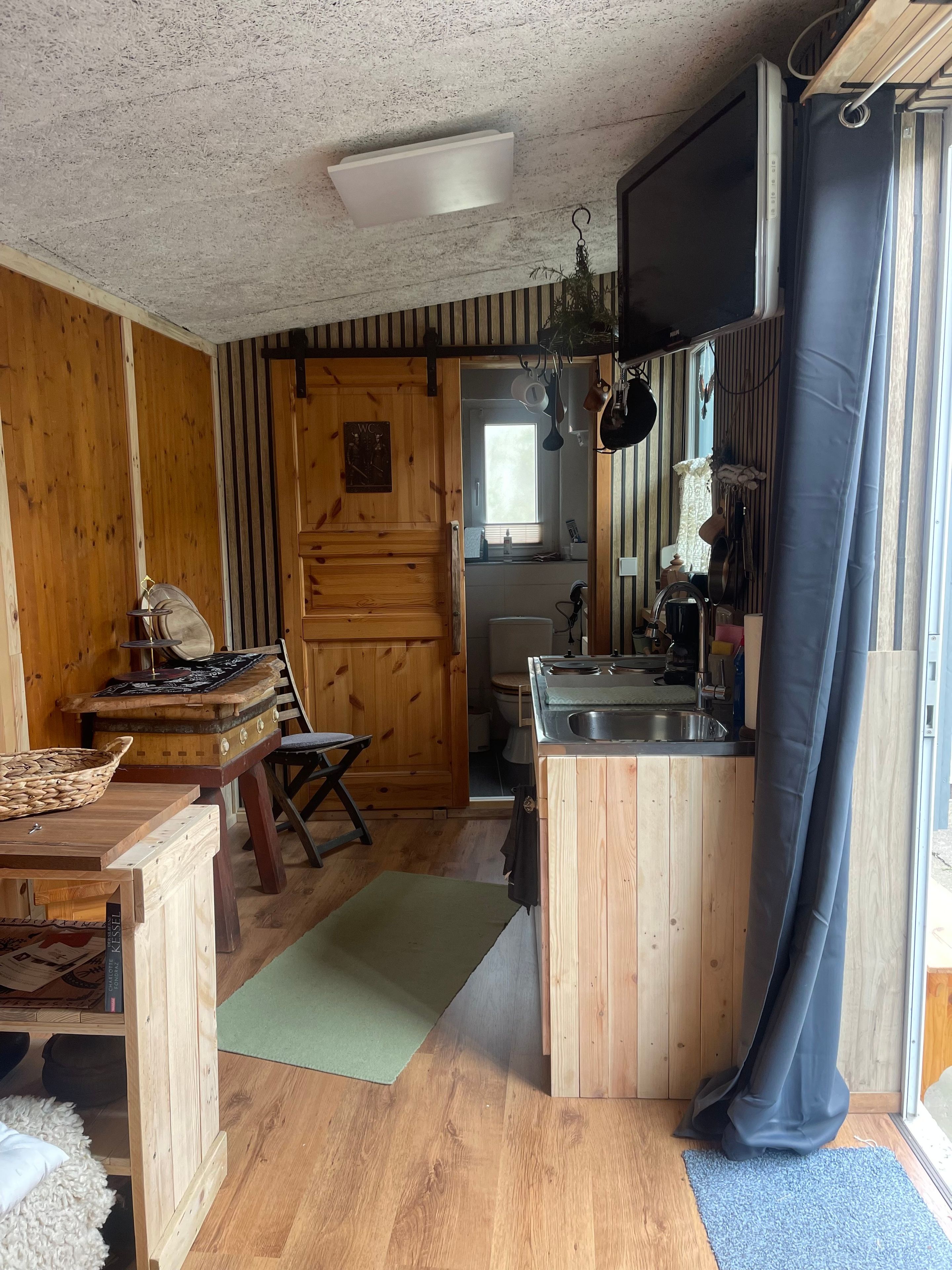 A wooden interior with a kitchen area, a dining table, and a small seating area.