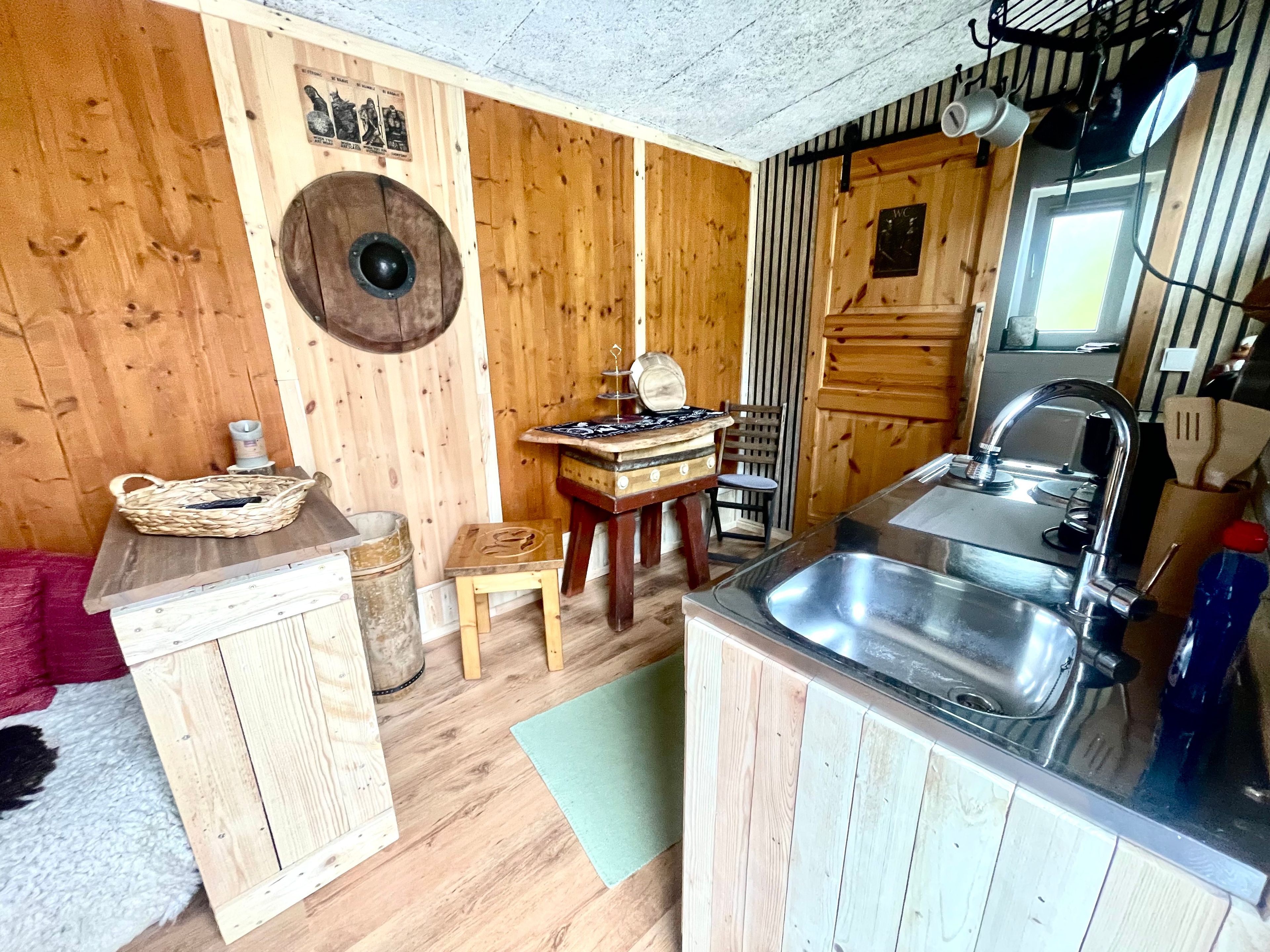 Une cuisine compacte avec des murs en bois, un évier, une petite table et une chaise.