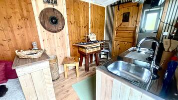 Une cuisine compacte avec des murs en bois, un évier, une petite table et une chaise.