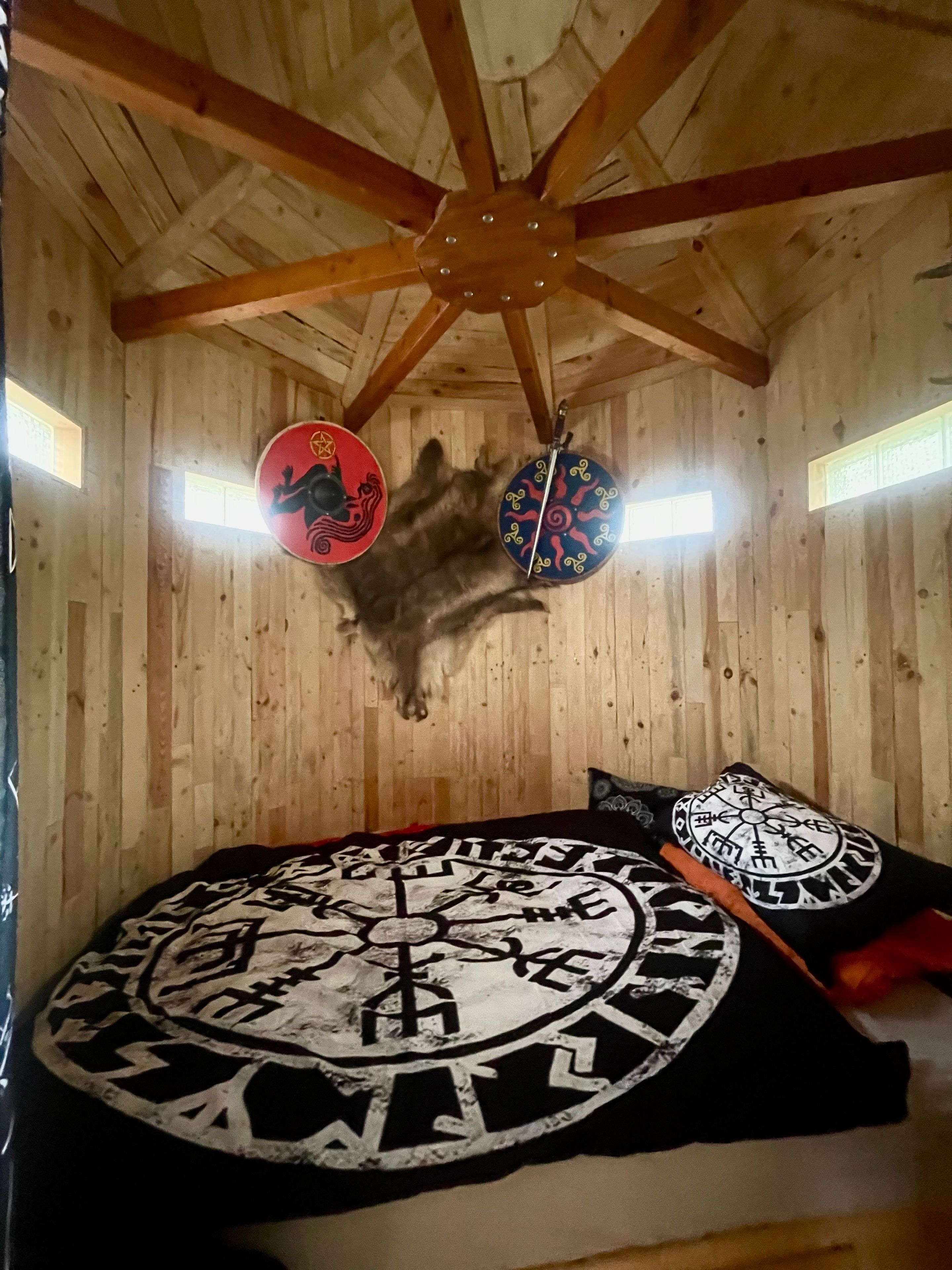 Een kamer met houten wanden, een plafondventilator en een groot rond vloerkleed met een ontwerp van een kompas.