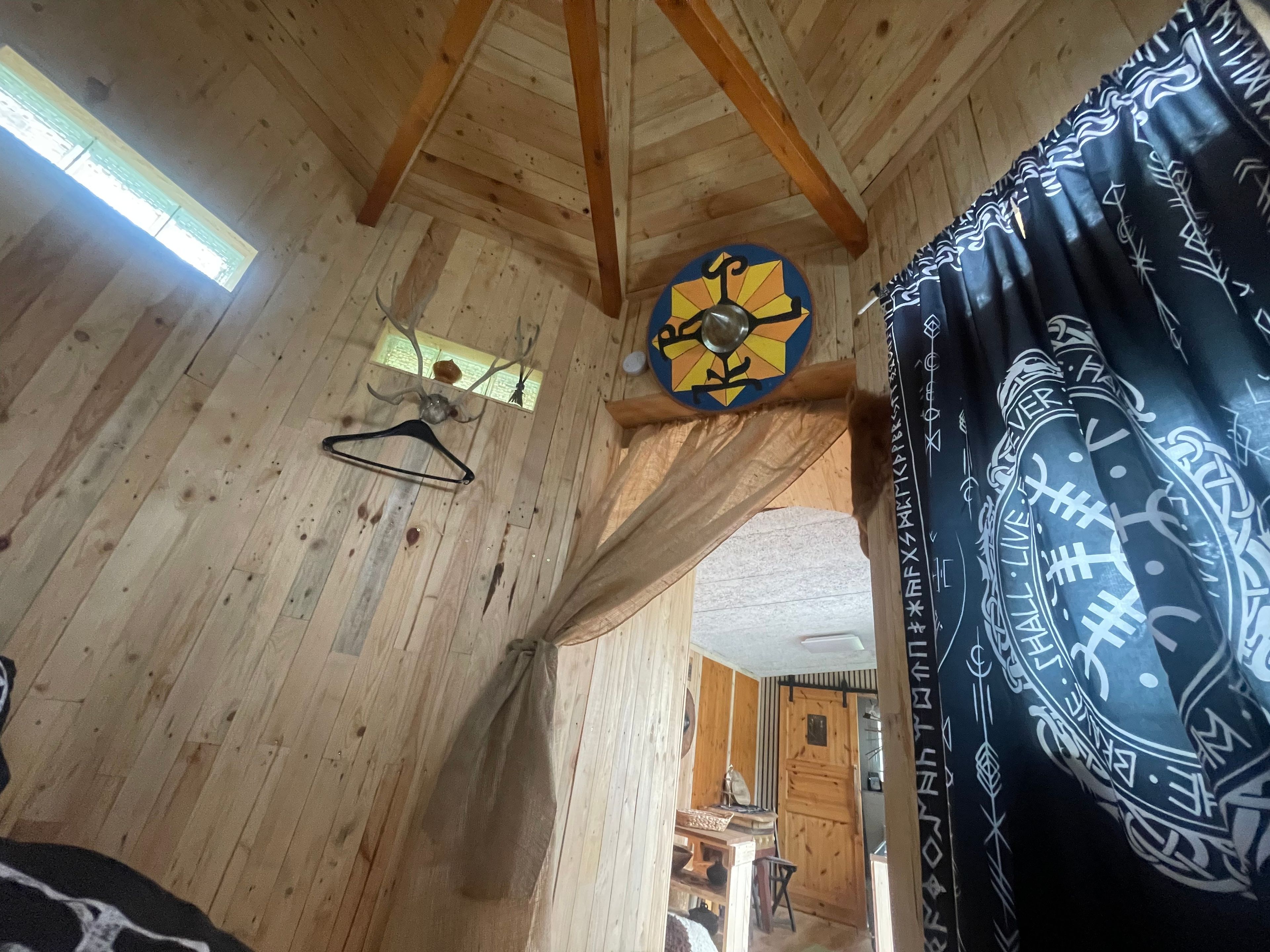Un intérieur en bois, avec un plafond en bois, un luminaire suspendu et un rideau à motifs.